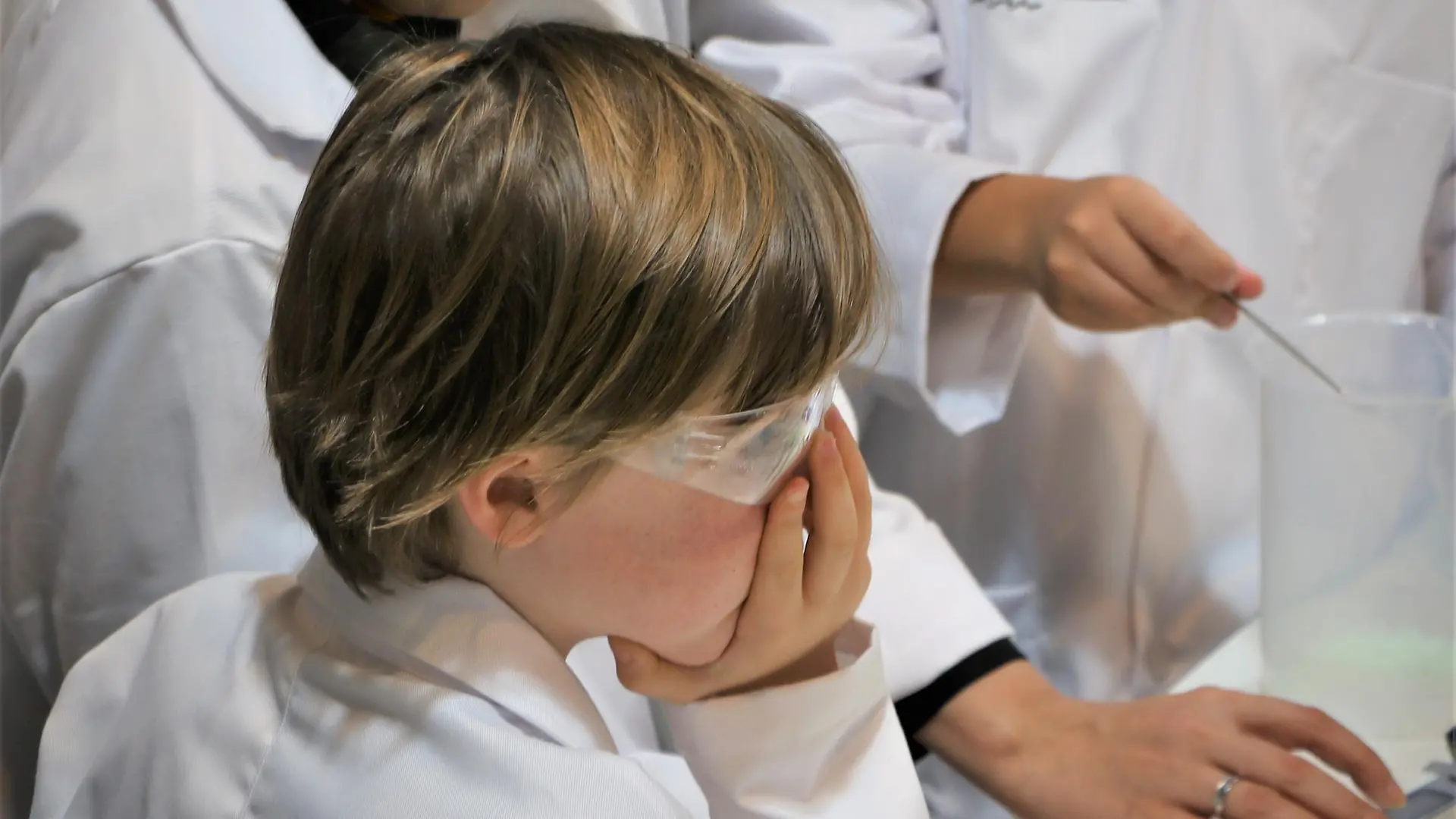 three children in lab coats with female teacher