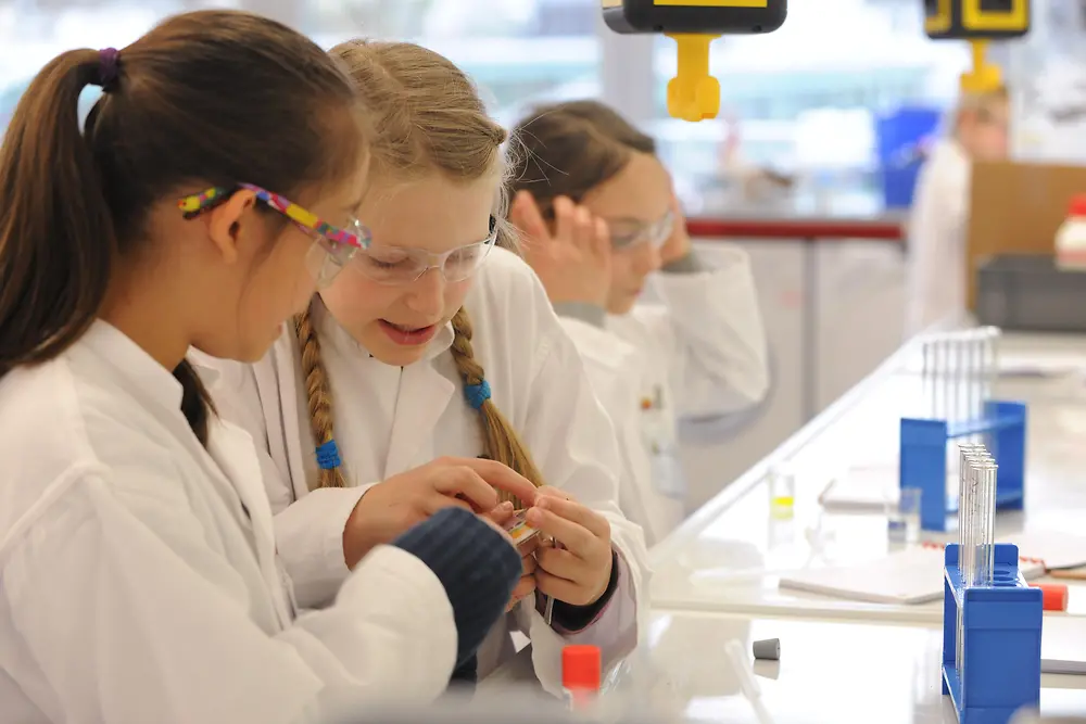 two girls in lab coats at bench