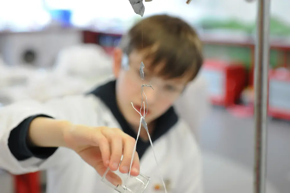 boy in lab coat besides a stand