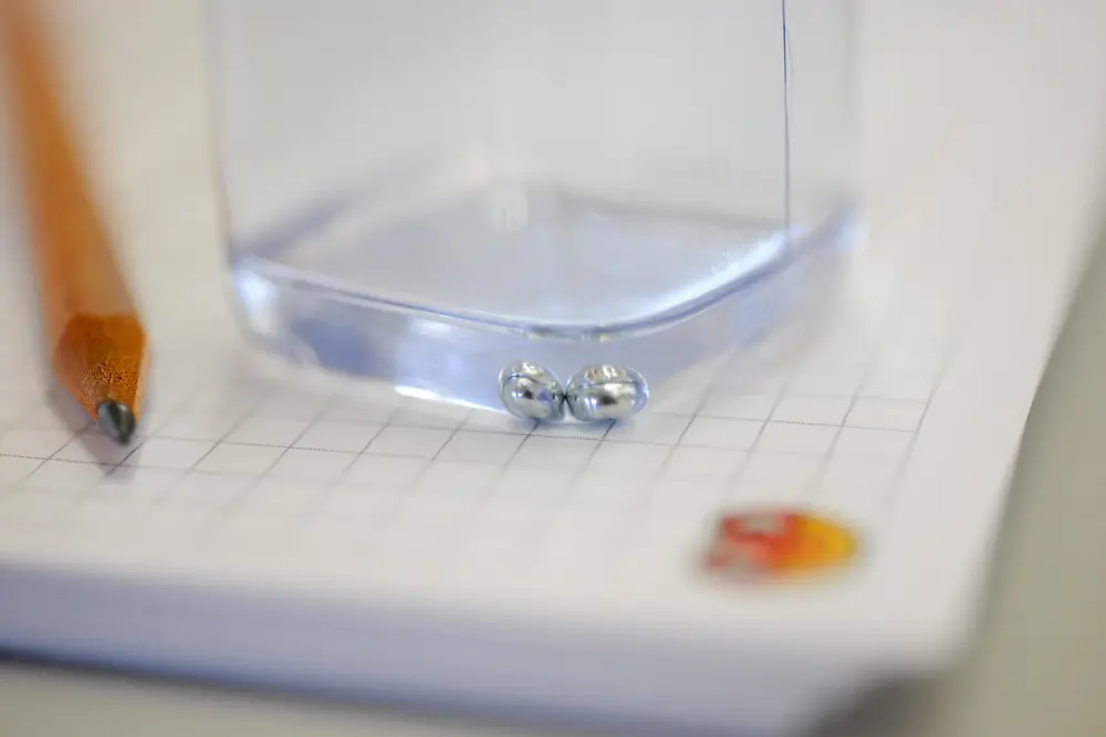 lower half of small container with a clear liquid standing on checkered paper