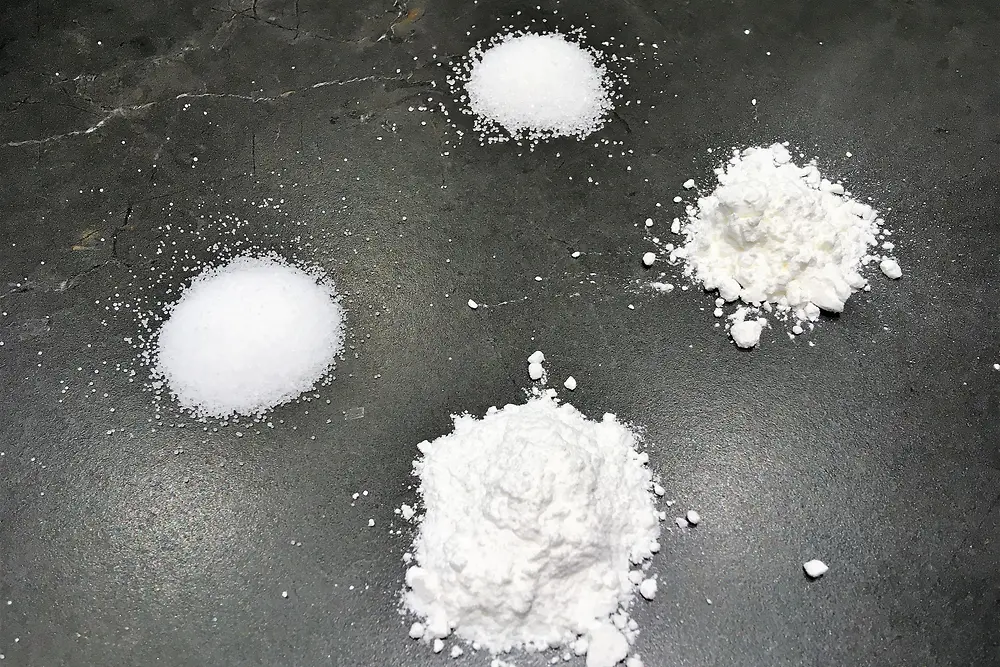 four white powders on black surface