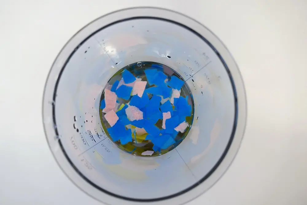 look from above into plastic jug containing colored pieces of paper