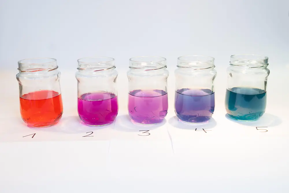 five glass jars with different colored liquids