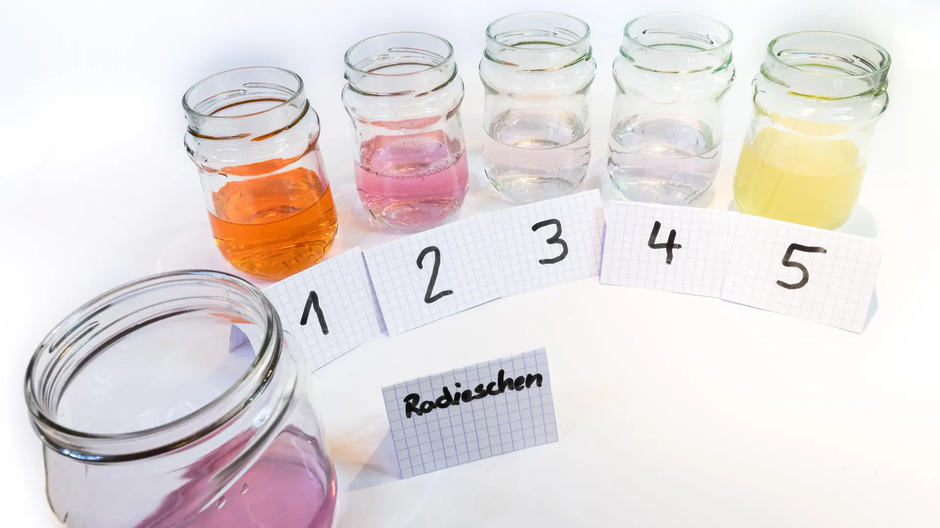 six glass jars with different colored liquids 