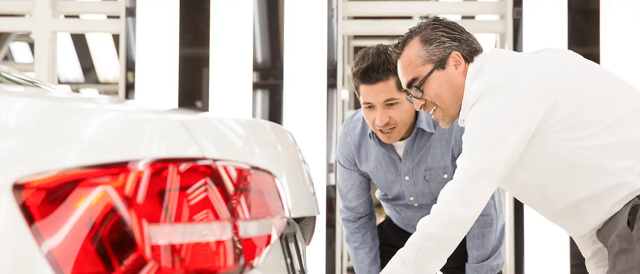 Zwei Männer überprüfen die Rückseite eines Autos.