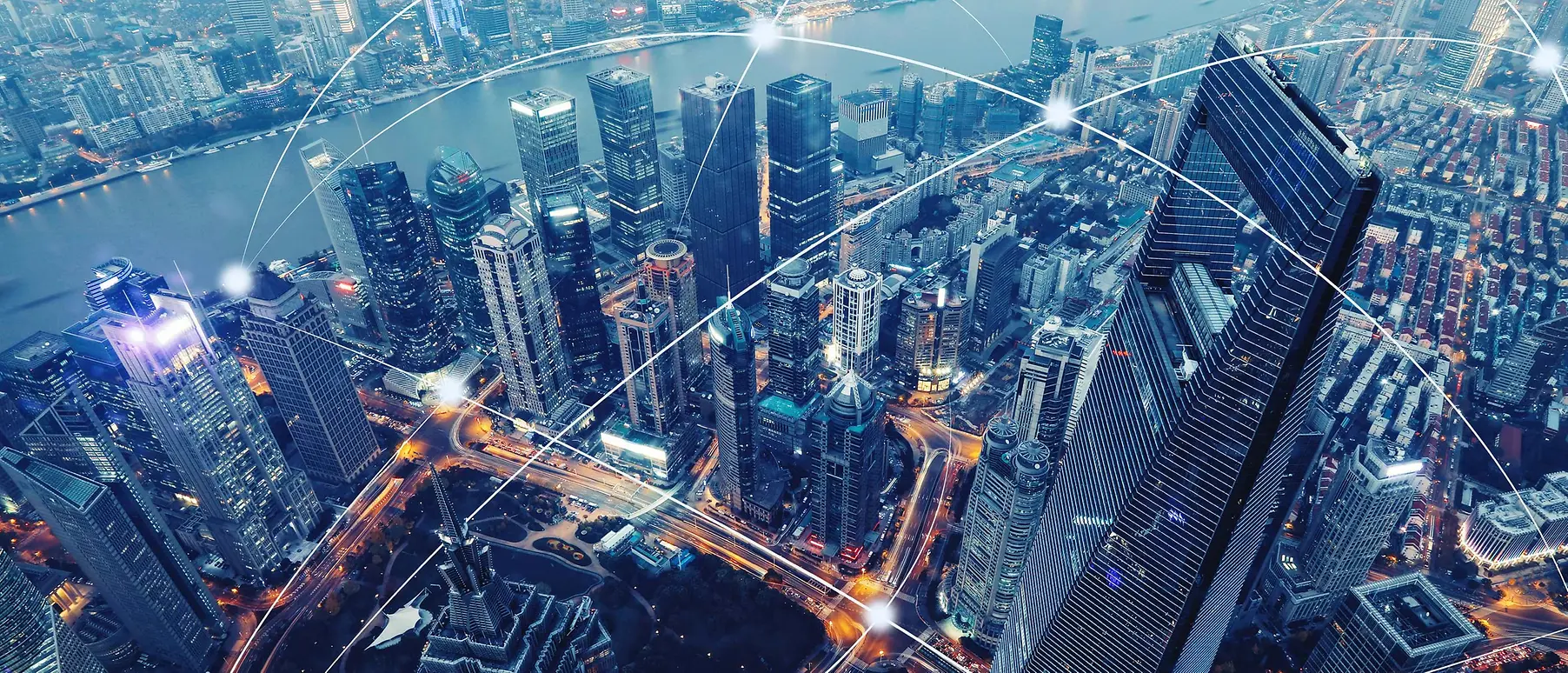 Bird´s eye view of Shangai´s skyscrapers. Several cruved white lines intersect each other above the city, representing connectivity.